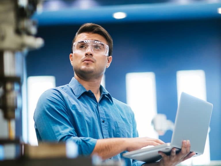 Engineer working on laptop and drill