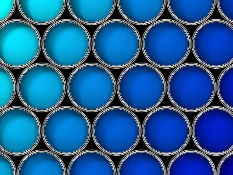 Numerous open paint tins filled with different shades of blue paint