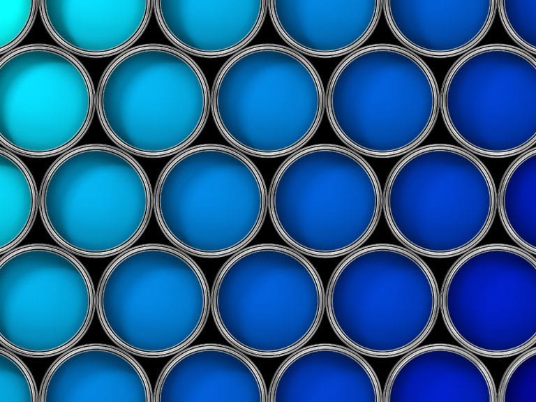 Numerous open paint tins filled with different shades of blue paint