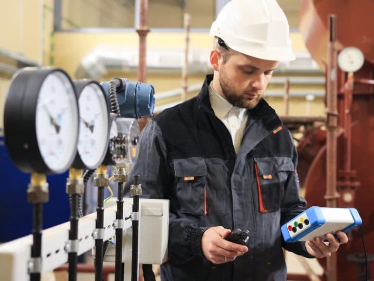 Technician operator measuring value of pressure, temperature and flow on gas and oil processing platform to monitor quality of process.